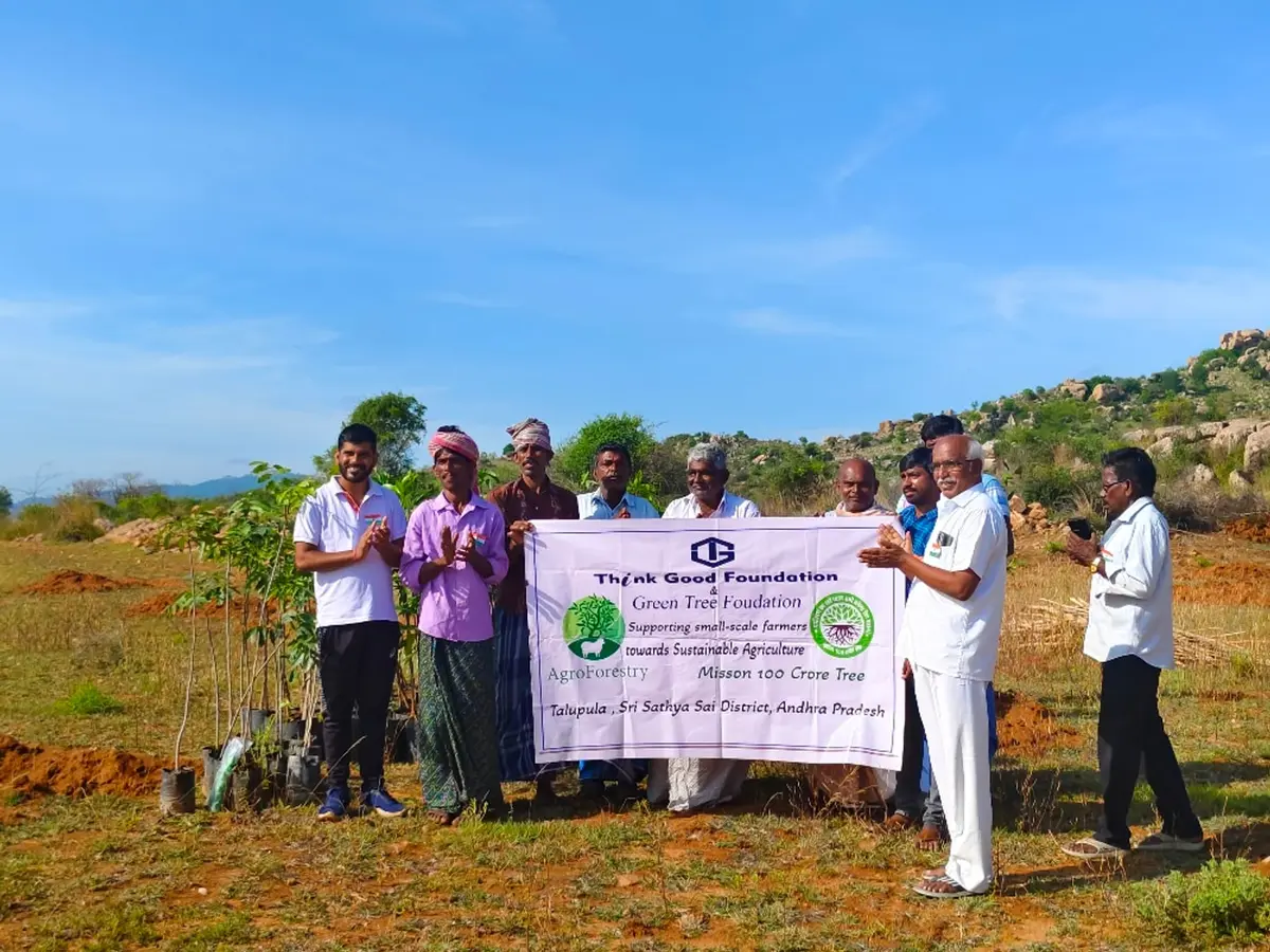 Farmers and foundation staff holding a programme banner beside mango saplings in Talupula, Andhra Pradesh